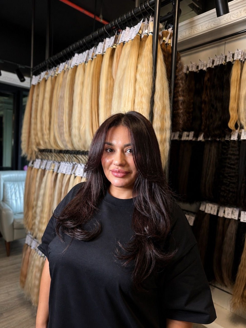 Finished multi-tone brunette extension blend in front of the ZORUMI hair wall
